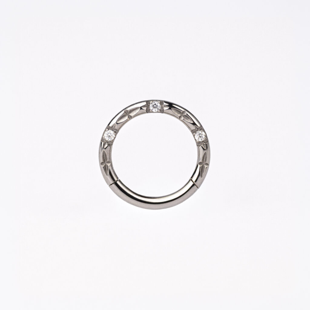 Anneau clicker en titane ASTM F-136, orné de zircons facettés, disponible en finition argentée ou dorée.