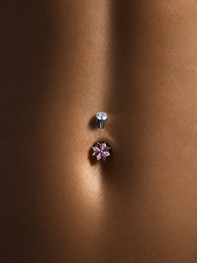 Piercing de nombril doré avec étoile en cristaux rouges et roses et zircone blanche.