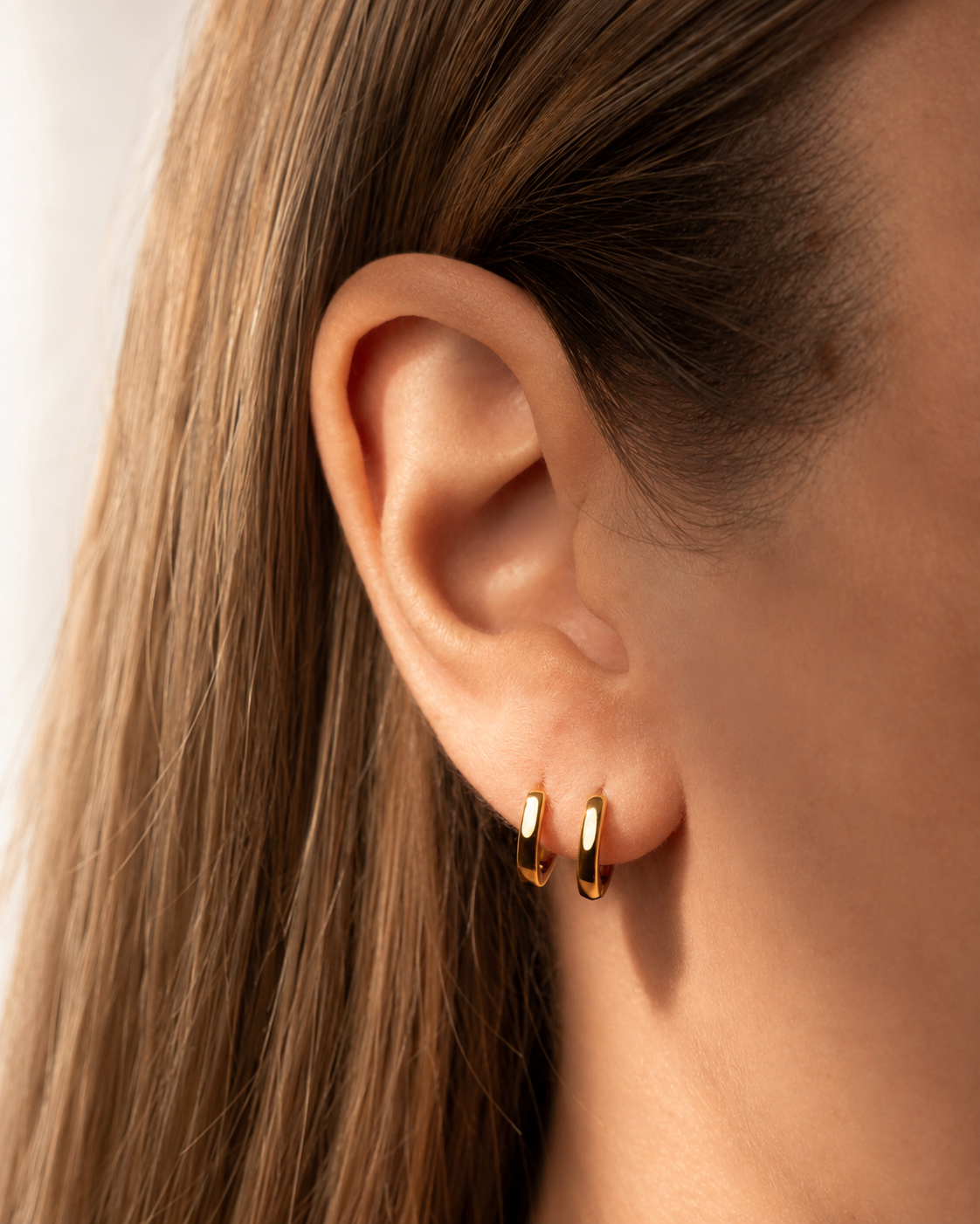 Boucles d’oreilles LYNEA en laiton recouvert d’or 18 carats, portées à l’oreille.